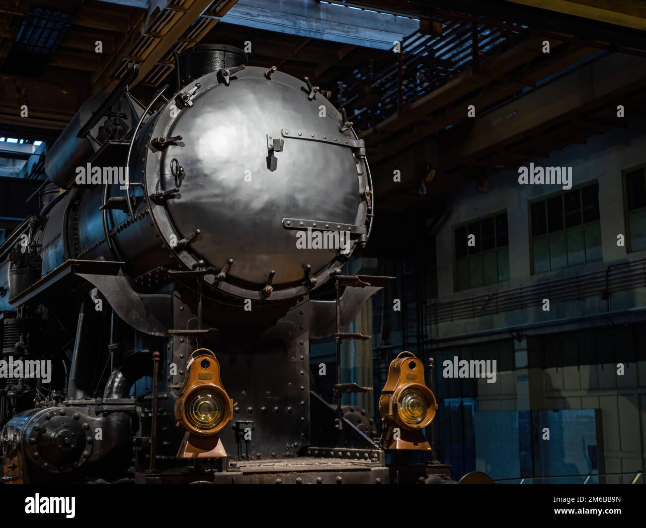 Vecchio treno a vapore nero in un hangar con belle lampade in ottone Foto Stock