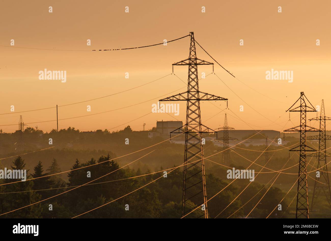 Le linee di alimentazione illuminato dal sole al tramonto Foto Stock