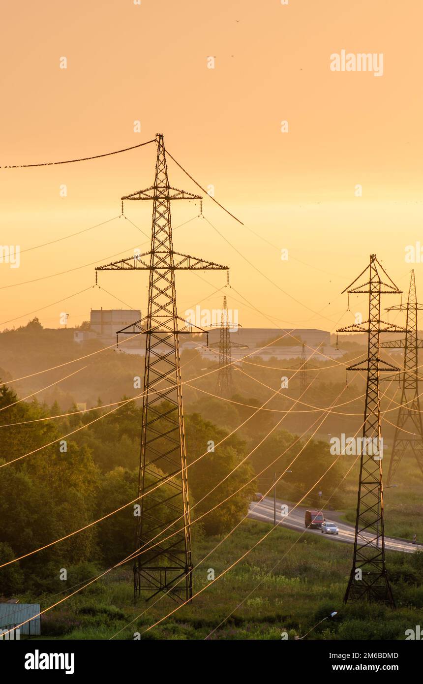 Le linee di alimentazione illuminato dal sole al tramonto Foto Stock