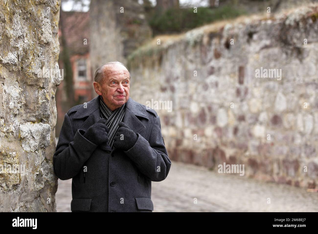 Uomo anziano che si trova alle mura di una storica città tedesca Foto Stock