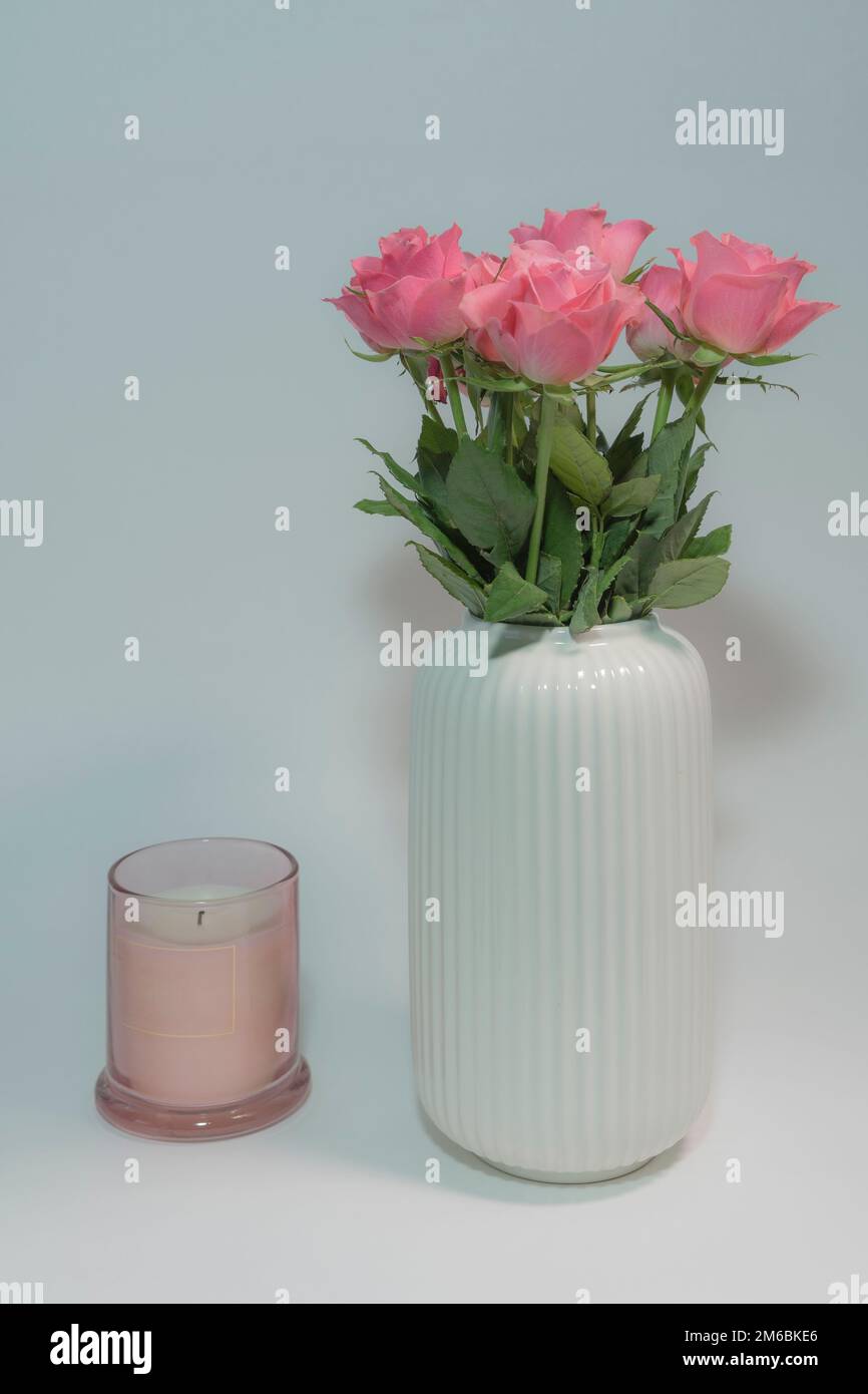 Rose rosa in vaso e candela spenta Foto Stock