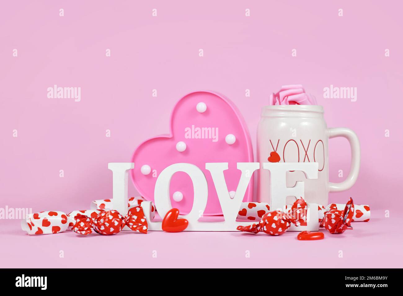Cute San Valentino decorazione con segno di testo di amore, cuori, caramella e tazza su sfondo rosa Foto Stock