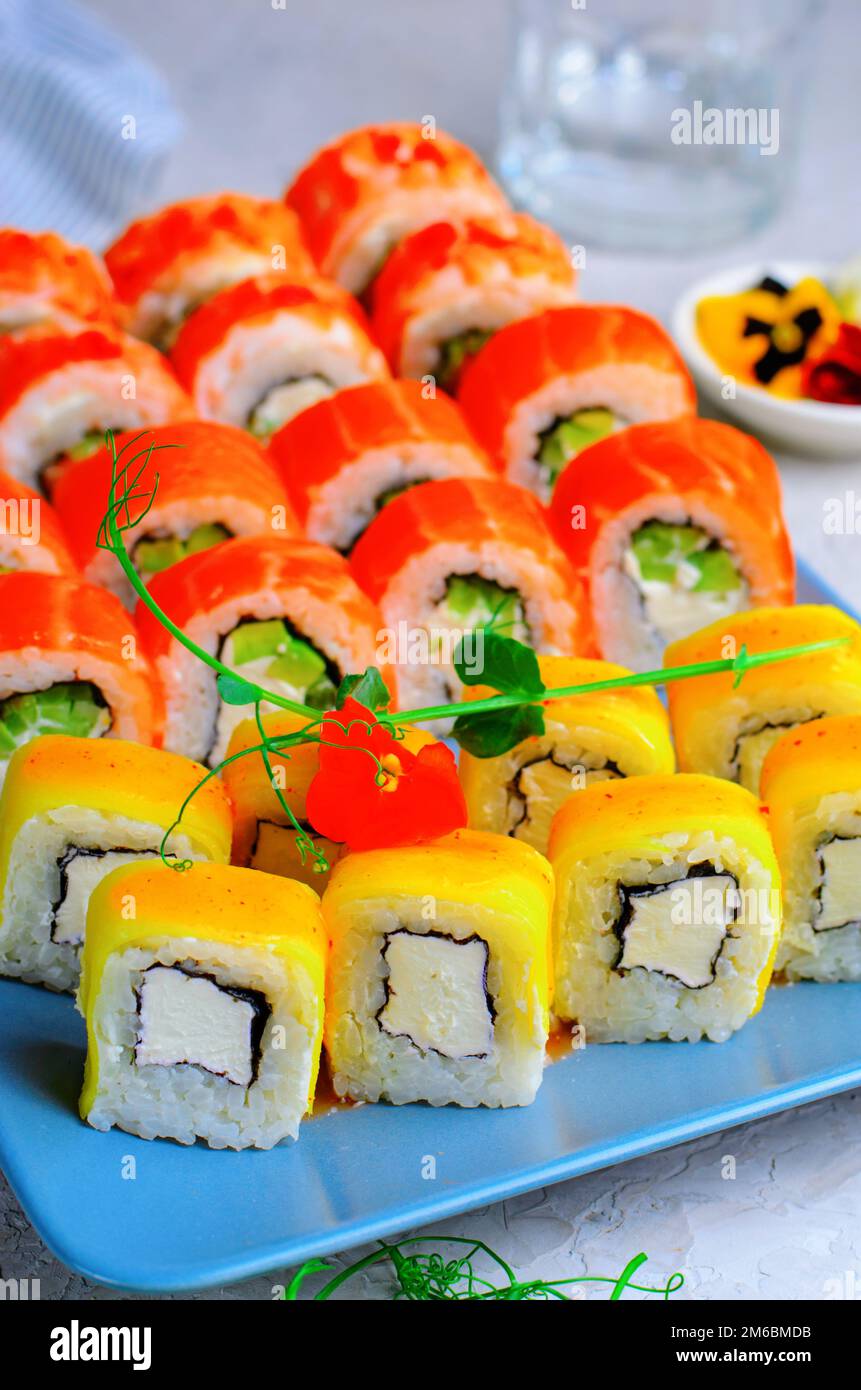 Sushi roll con salmone, gamberi e mango su sfondo azzurro, cucina giapponese, piatti asiatici Foto Stock