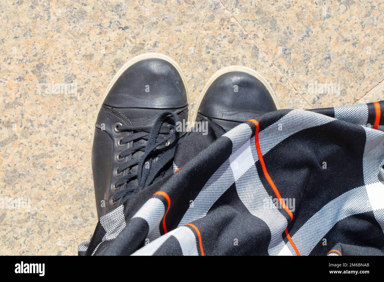 sneakers neri e un lungo vestito sul pavimento nella moschea vista dall'alto da vicino Foto Stock