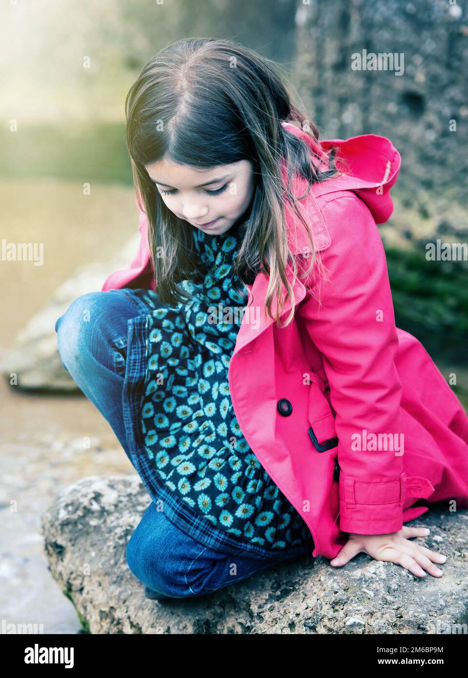 Bella bambina che gioca su una roccia al bordo dell'acqua Foto Stock