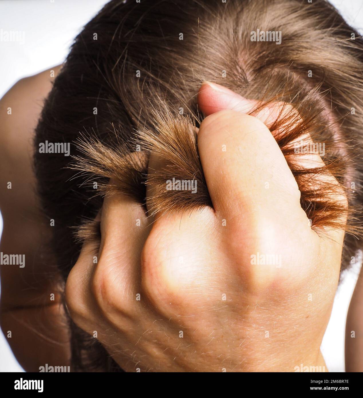 Primo piano della mano che tira i capelli dalla testa di una persona maschile Foto Stock