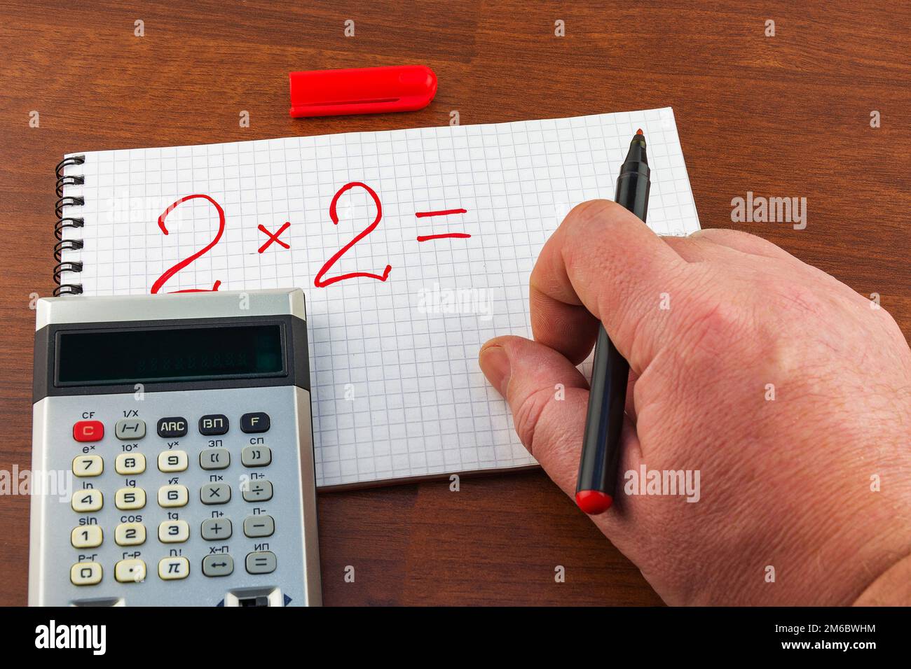 L'equazione di scrittura della mano dell'uomo sul foglio del taccuino in una gabbia Foto Stock