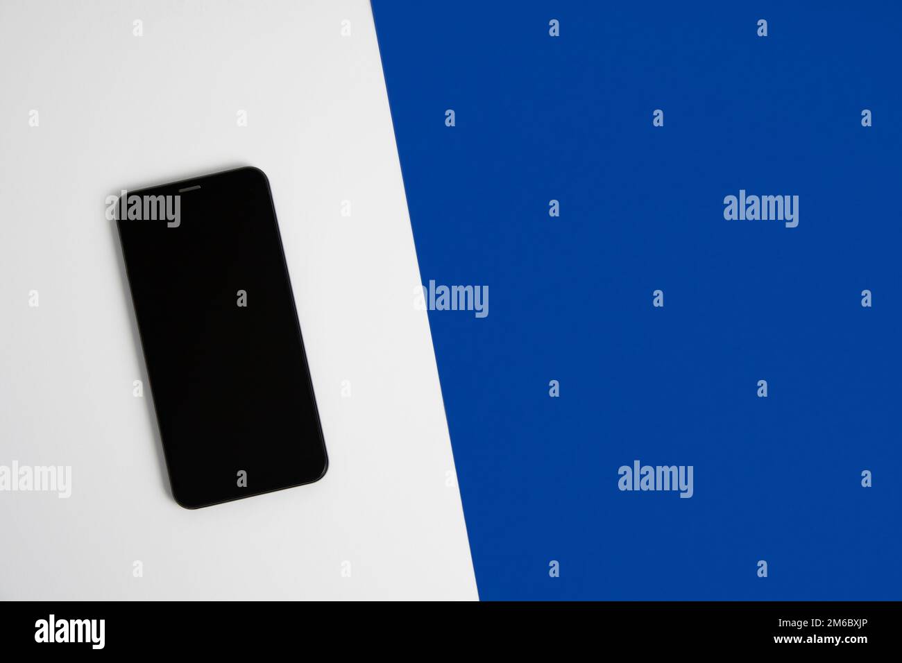 Smartphone su sfondo bianco e blu primo piano dall'alto Foto Stock