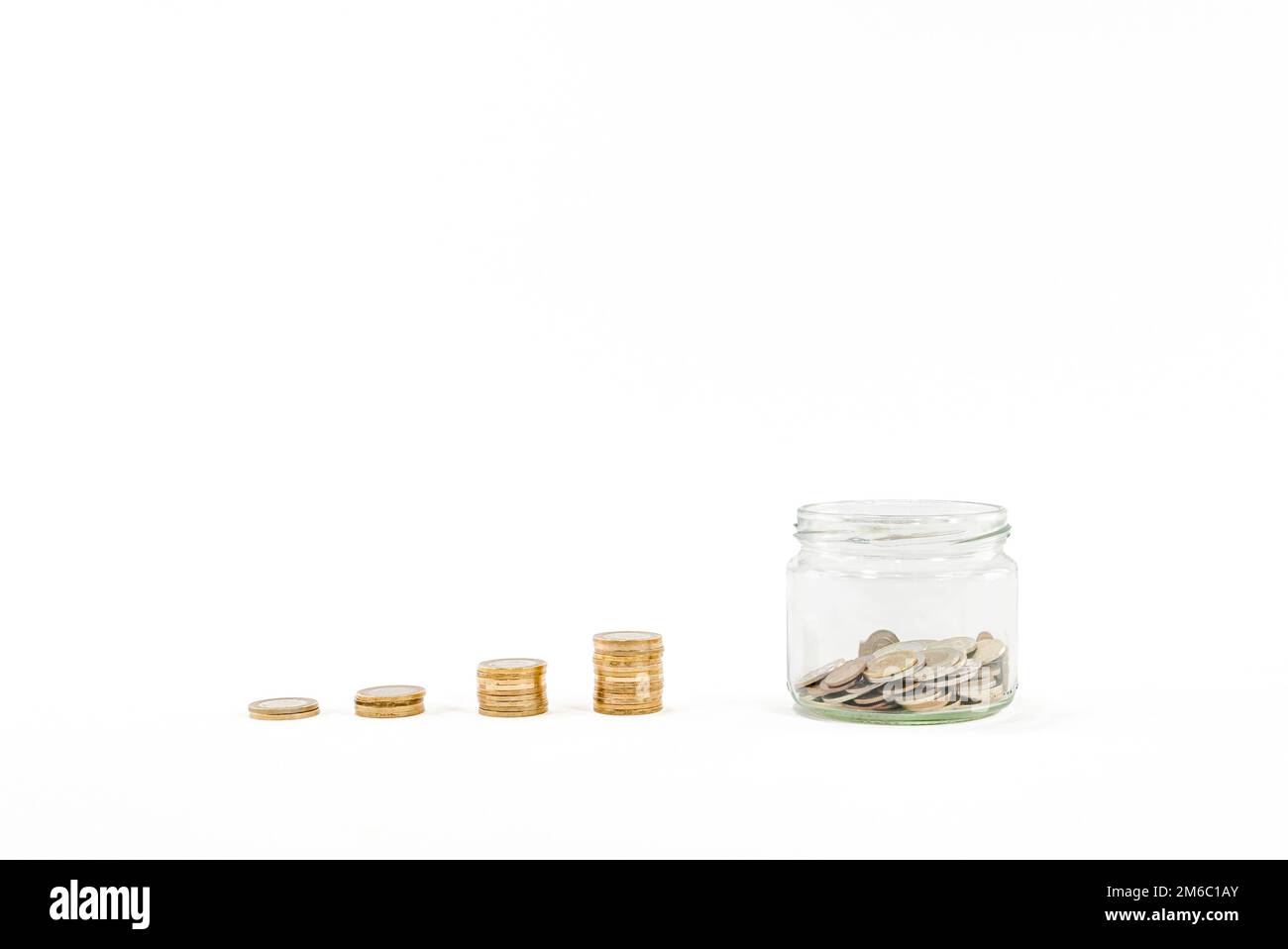 Vaso di vetro trasparente con monete impilate scatola di denaro, penny o piggy banca su sfondo bianco. Risparmio di denaro idea foto hd. Risparmio di denaro scatola o piggy. Foto Stock