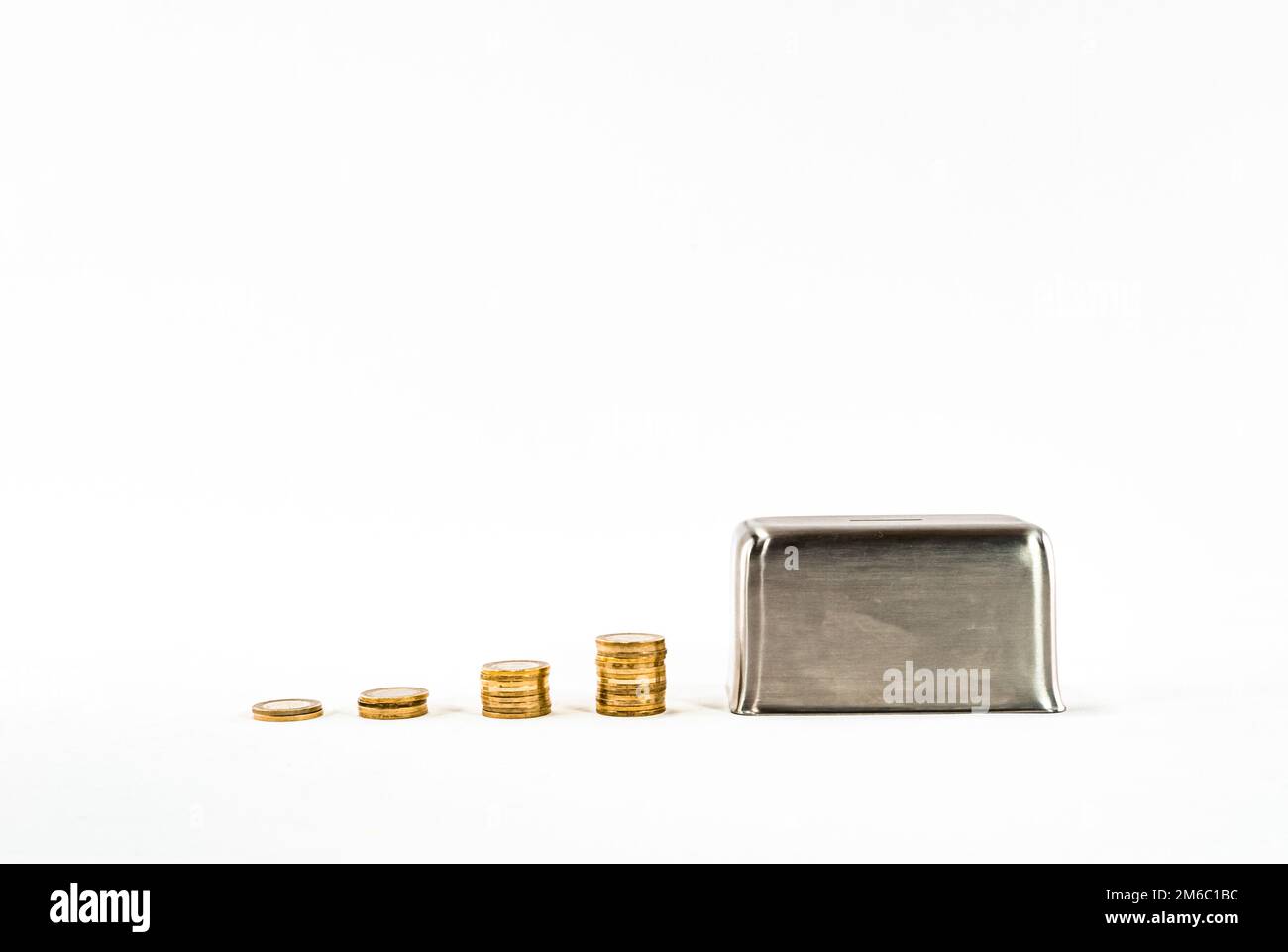 Cassetta di metallo in acciaio con monete impilate, penny o piggy bank su sfondo bianco. Risparmio di denaro idea foto hd. Risparmio di denaro scatola o piggy bank Foto Stock