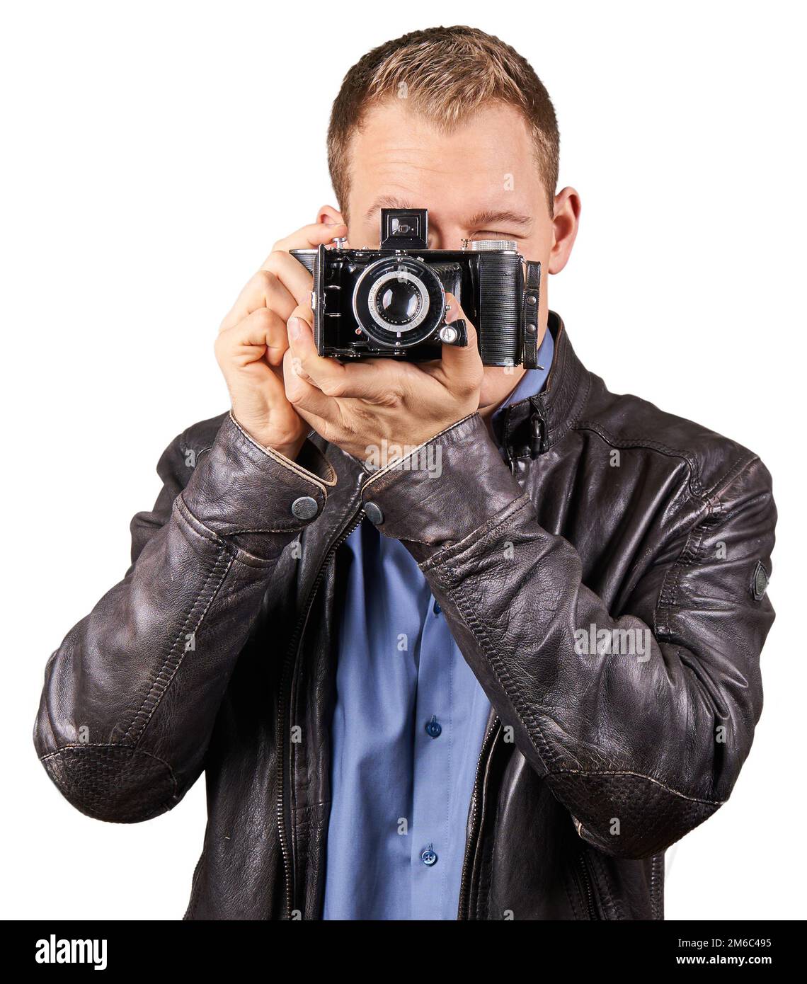 Giovane con una giacca di pelle con una vecchia fotocamera vintage e orientata verso la telecamera - isolato. Foto Stock