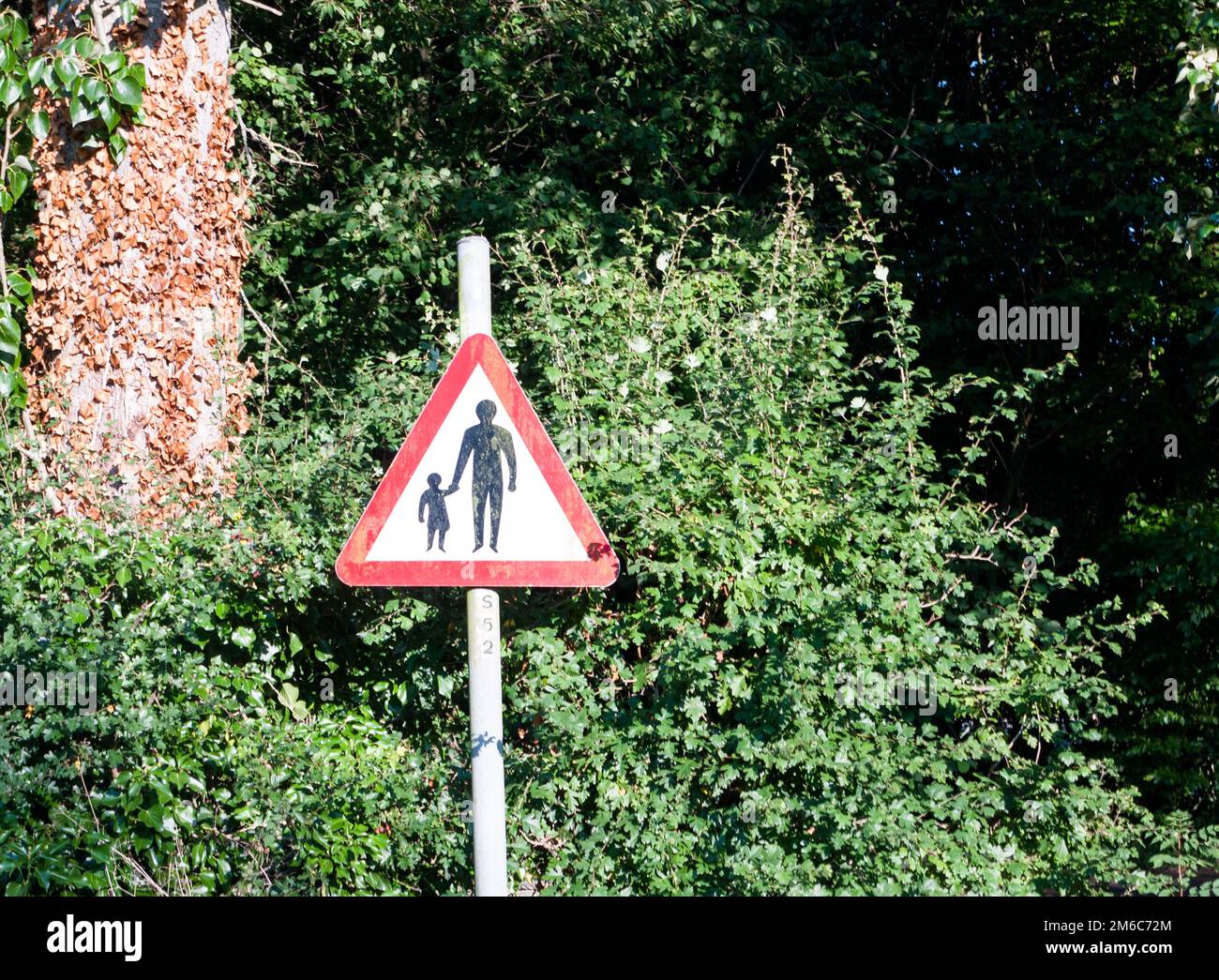 Un cartello stradale a triangolo rosso con un'avvertenza per la sicurezza di uomo e bambino Foto Stock