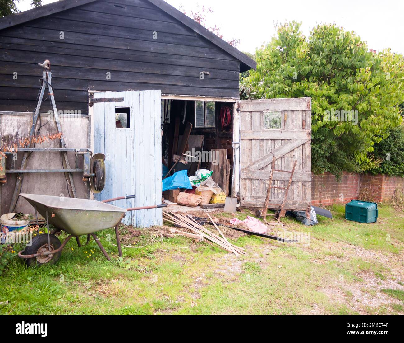Un capannone in legno aperto in campagna con attrezzi e attrezzature in fattoria Foto Stock