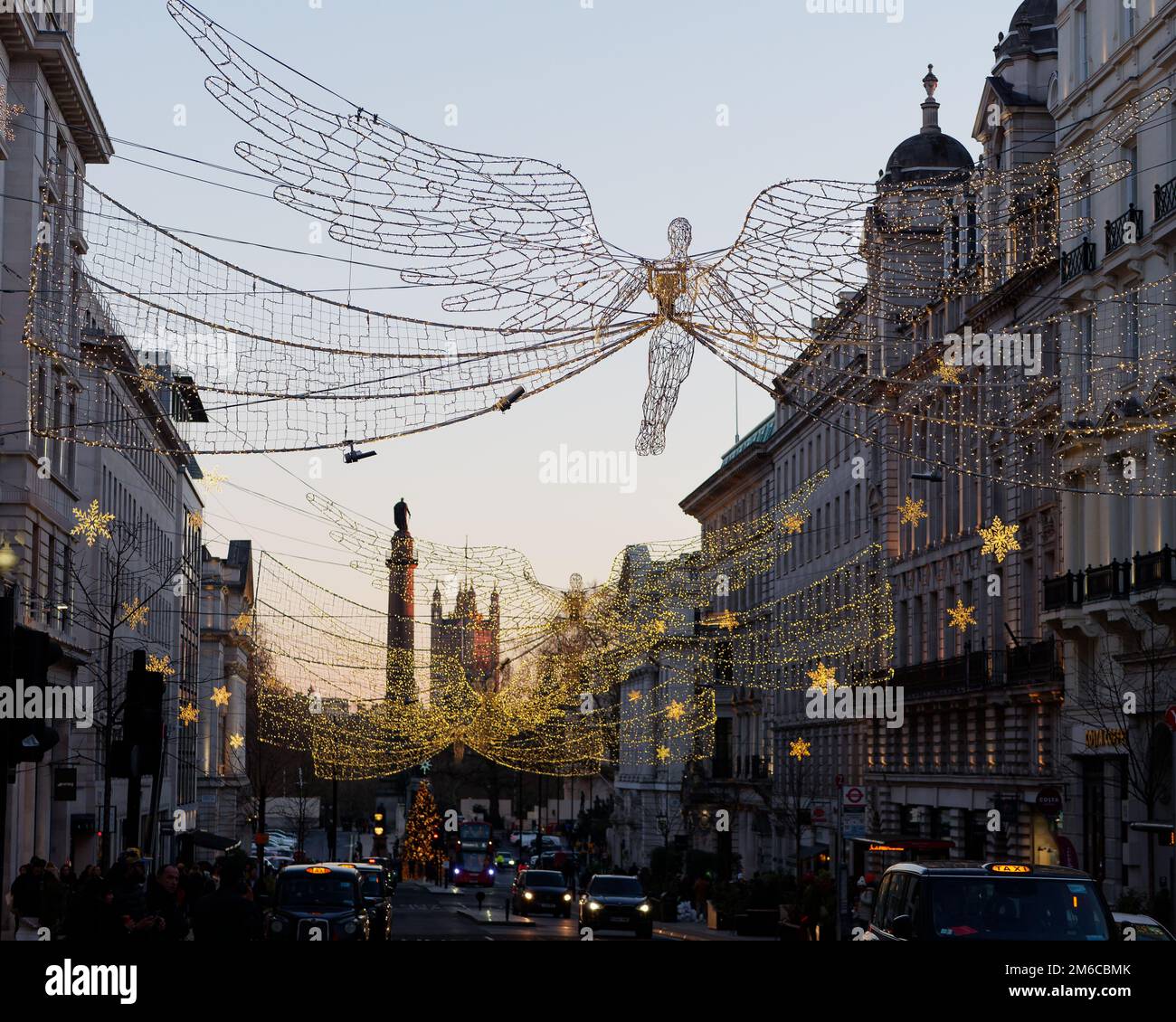 Spiriti di Natale appesi su Regent Street St James. Waterloo Place and Houses of Parliament dietro Londra, Inghilterra. Foto Stock