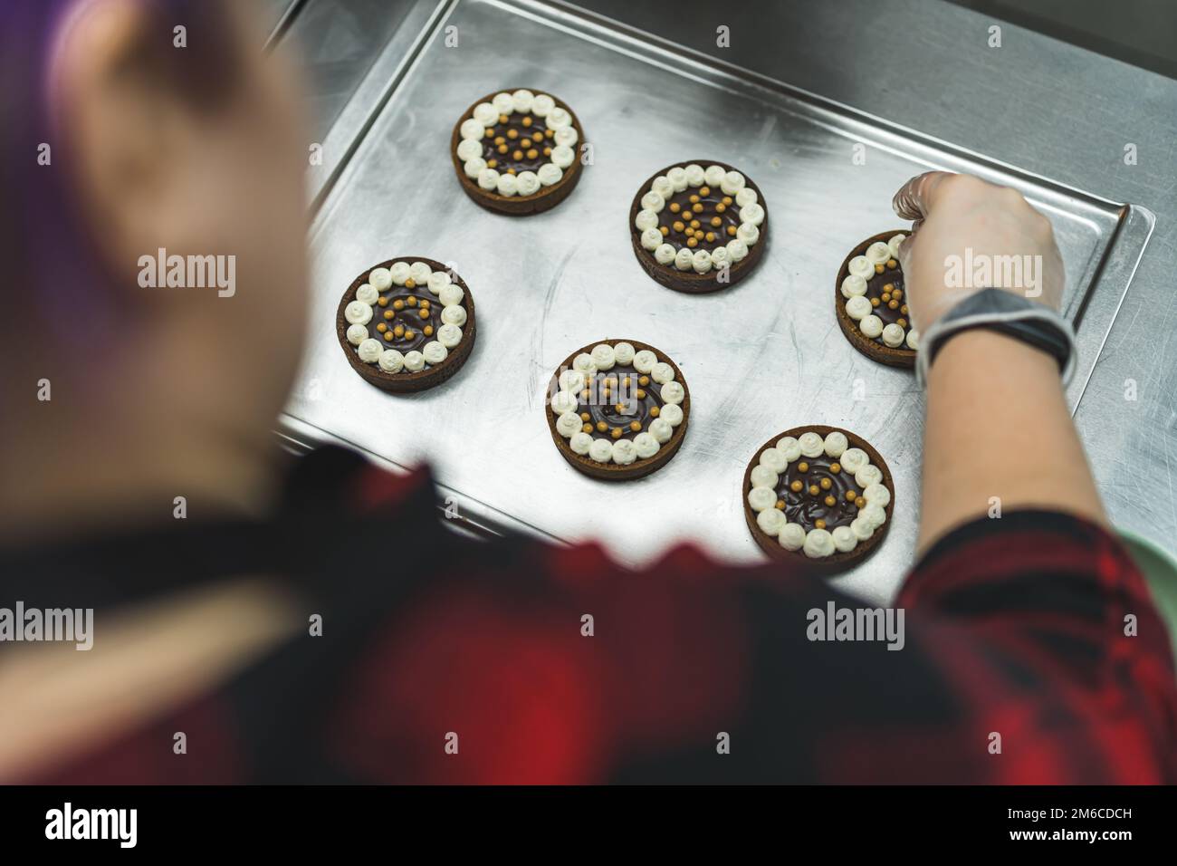 POV di Baker. Focalizzata pasticceria caucasica decorare mini crostate di cioccolato con perle commestibili. Spazio di copia. Foto di alta qualità Foto Stock