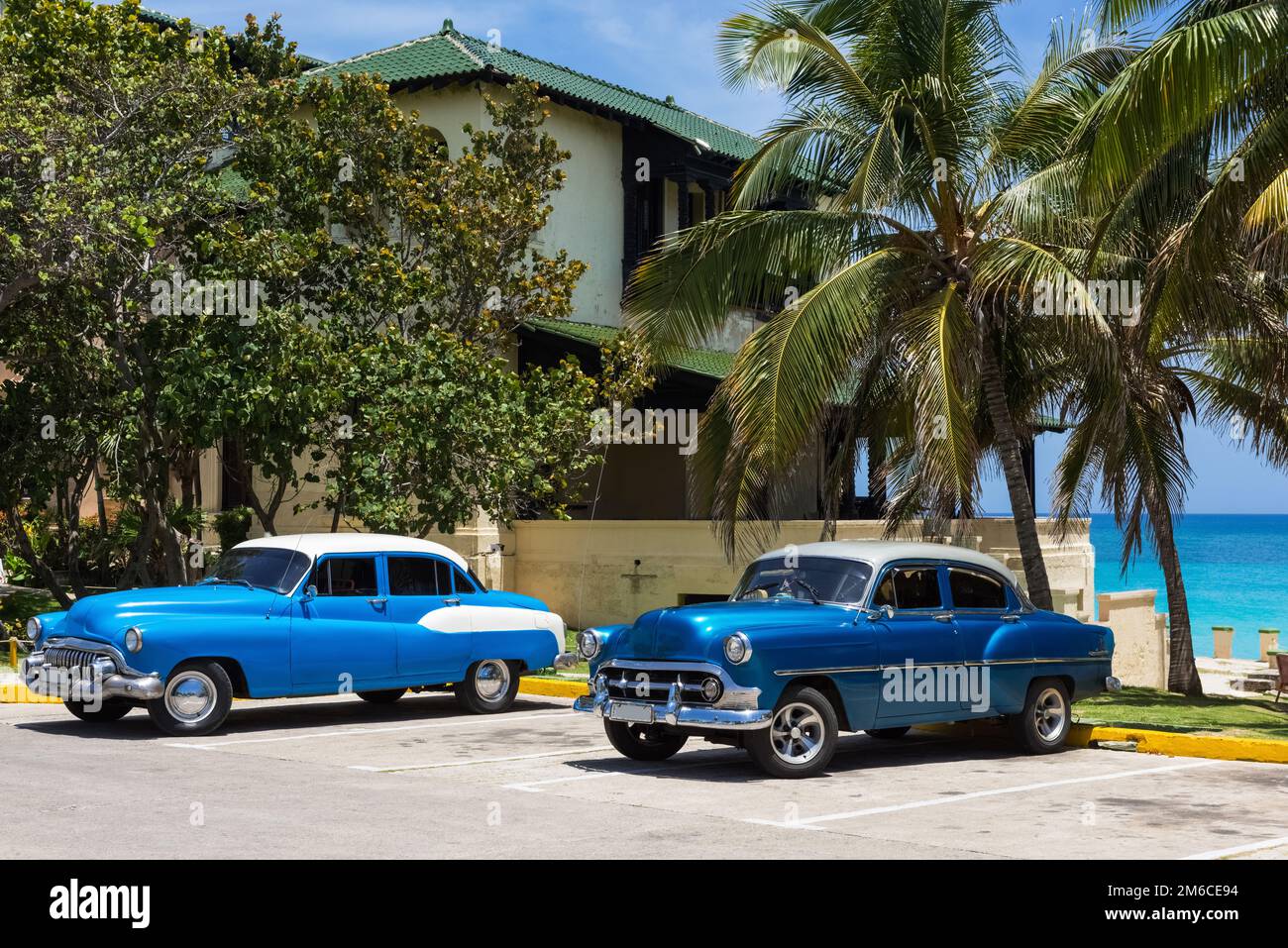 Auto classiche blu americane con rofo bianco parcheggiato sulla spiaggia sotto le palme a Varadero Cuba Foto Stock