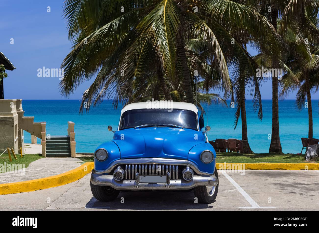 American Blue auto classica parcheggiata sotto le palme sulla spiaggia di Varadero Cuba -Serie Cuba R Foto Stock