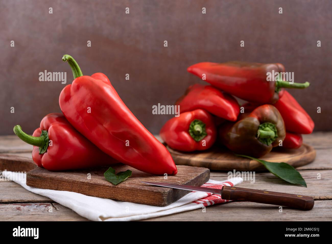 Taglieri con peperoni rossi dolci e foglie verdi su tavola di legno. Messa a fuoco selettiva. Foto Stock
