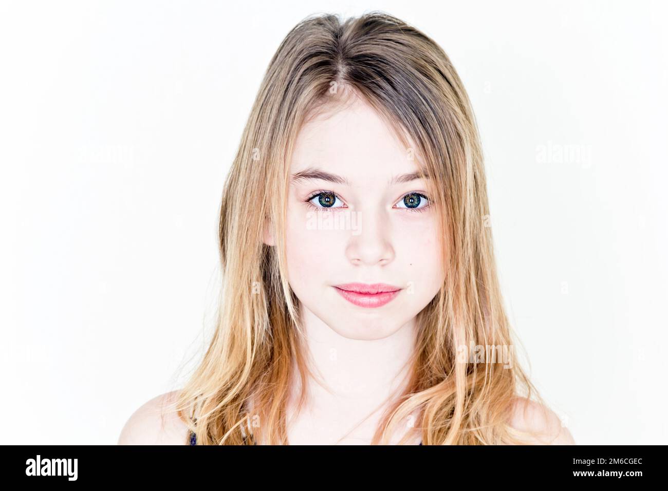 Ragazza adolescente con capelli lunghi biondi e grandi occhi sulla parete bianca Foto Stock