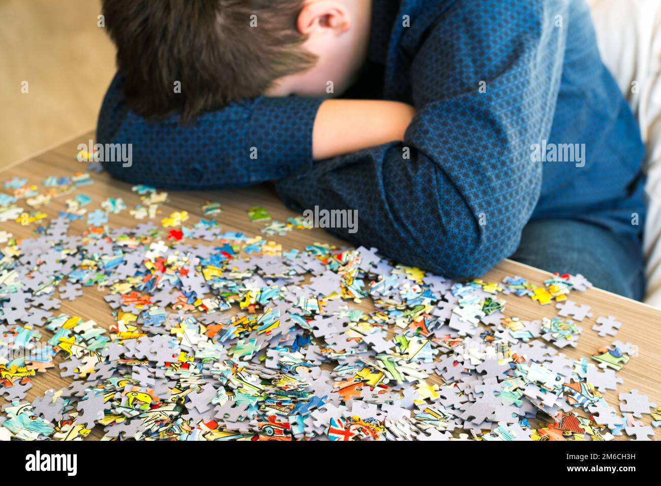 L'adolescente stanco è seduto inclinando la testa accanto a puzzle Foto Stock