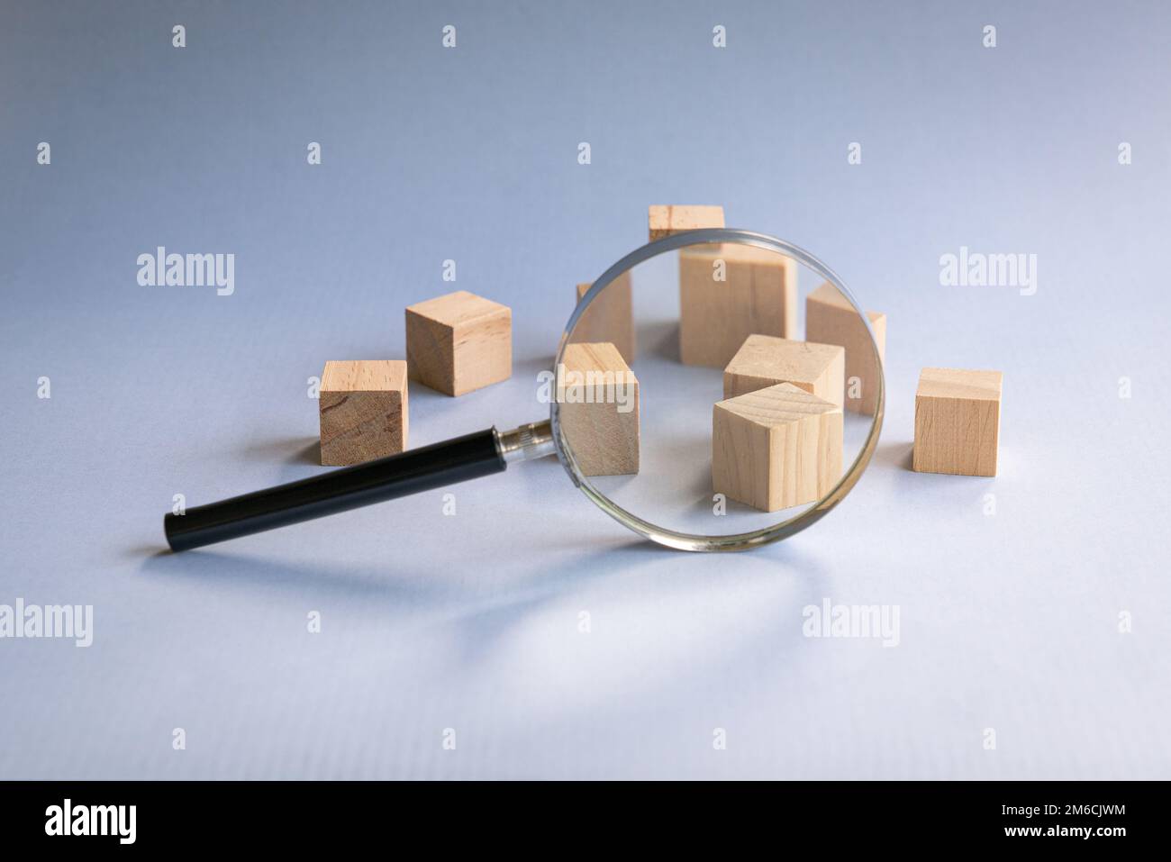 Lente d'ingrandimento con blocchi di legno. Costruzione, sviluppo o concetto di risorse umane. Foto Stock