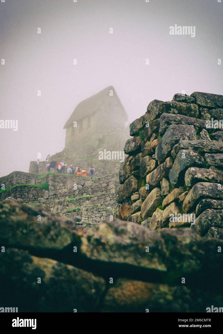 Turisti colorati in Machu Picchu rovine nella nebbia. Foto Stock