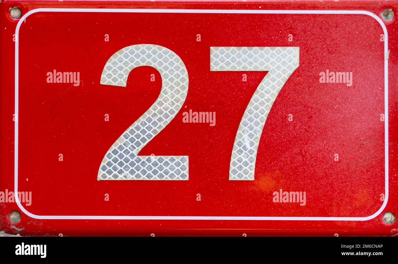 Numero 27. Targa rossa con numero ventisette su una parete. Foto Stock