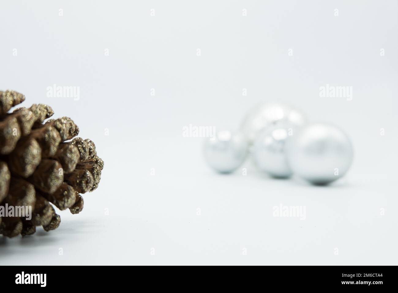 Palline bianche di Natale su sfondo bianco con cono di pino. Foto Stock