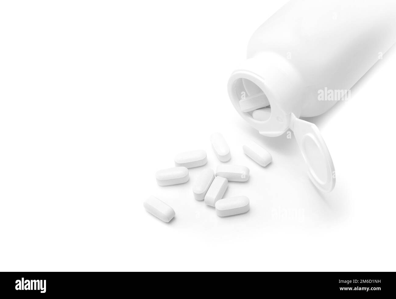 Pillole di bianco si versato da una bottiglia aperta Foto Stock