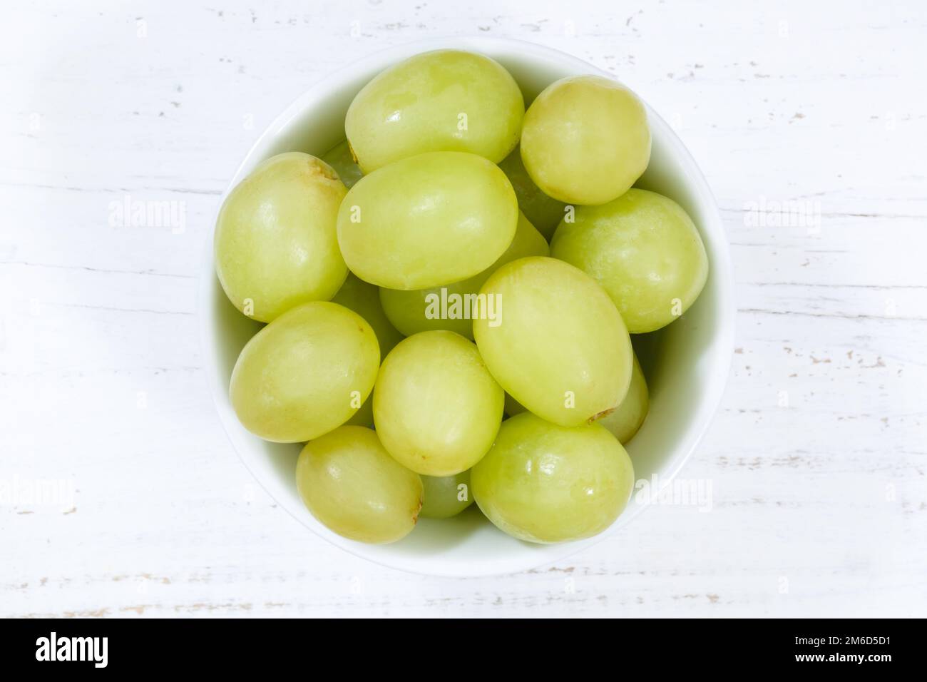 Uva frutta verde da sopra ciotola tavola di legno Foto Stock