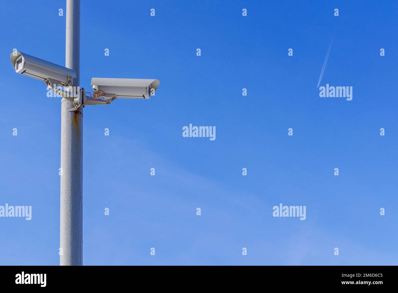 Due telecamere di sicurezza contro il cielo blu stanno monitorando. Foto Stock