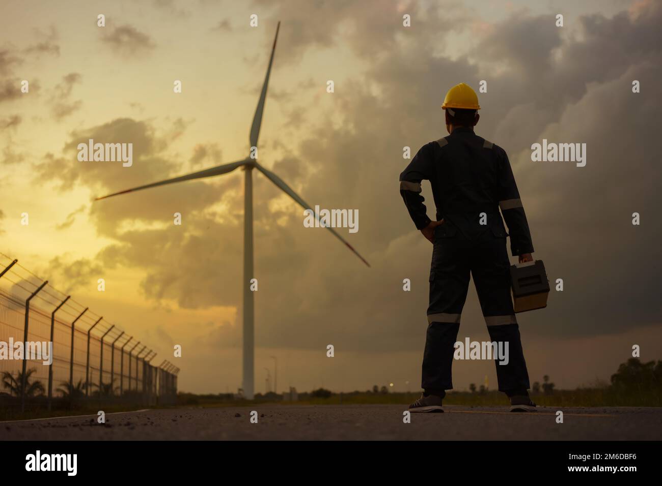 Tecnici addetti all'ispezione preparano e controllano lo stato di avanzamento di una turbina eolica con sicurezza in un parco eolico al tramonto. Foto Stock Tecnici addetti all'ispezione preparano e controllano lo stato di avanzamento di una turbina eolica con sicurezza in un parco eolico al tramonto. Foto Stock