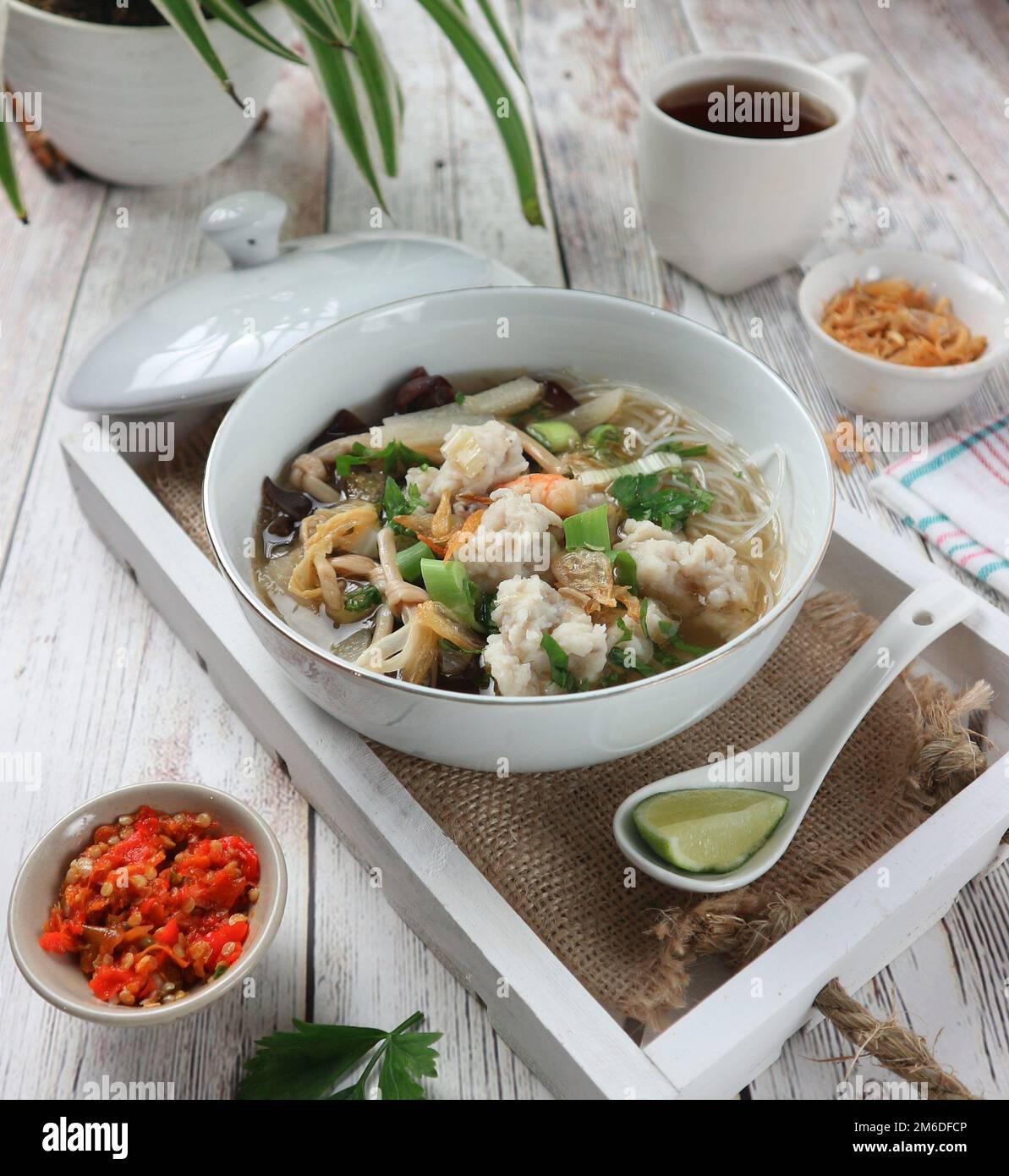 Zuppa di pesce alla palla servita con salsa di peperoncino e spicchi di lime Foto Stock