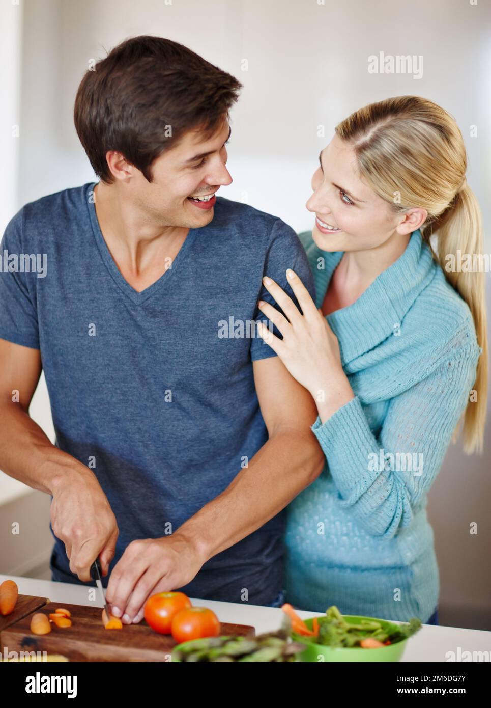 L'ingrediente segreto è l'amore. una giovane coppia felice che condivide un momento affettuoso insieme mentre prepara un pasto. Foto Stock