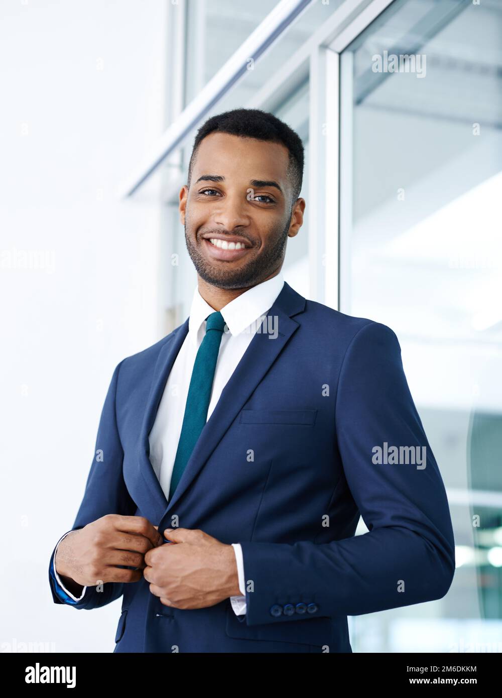 Il successo inizia con il giusto abbigliamento. Un bel giovane uomo  d'affari afroamericano in piedi al coperto con un sorriso Foto stock - Alamy
