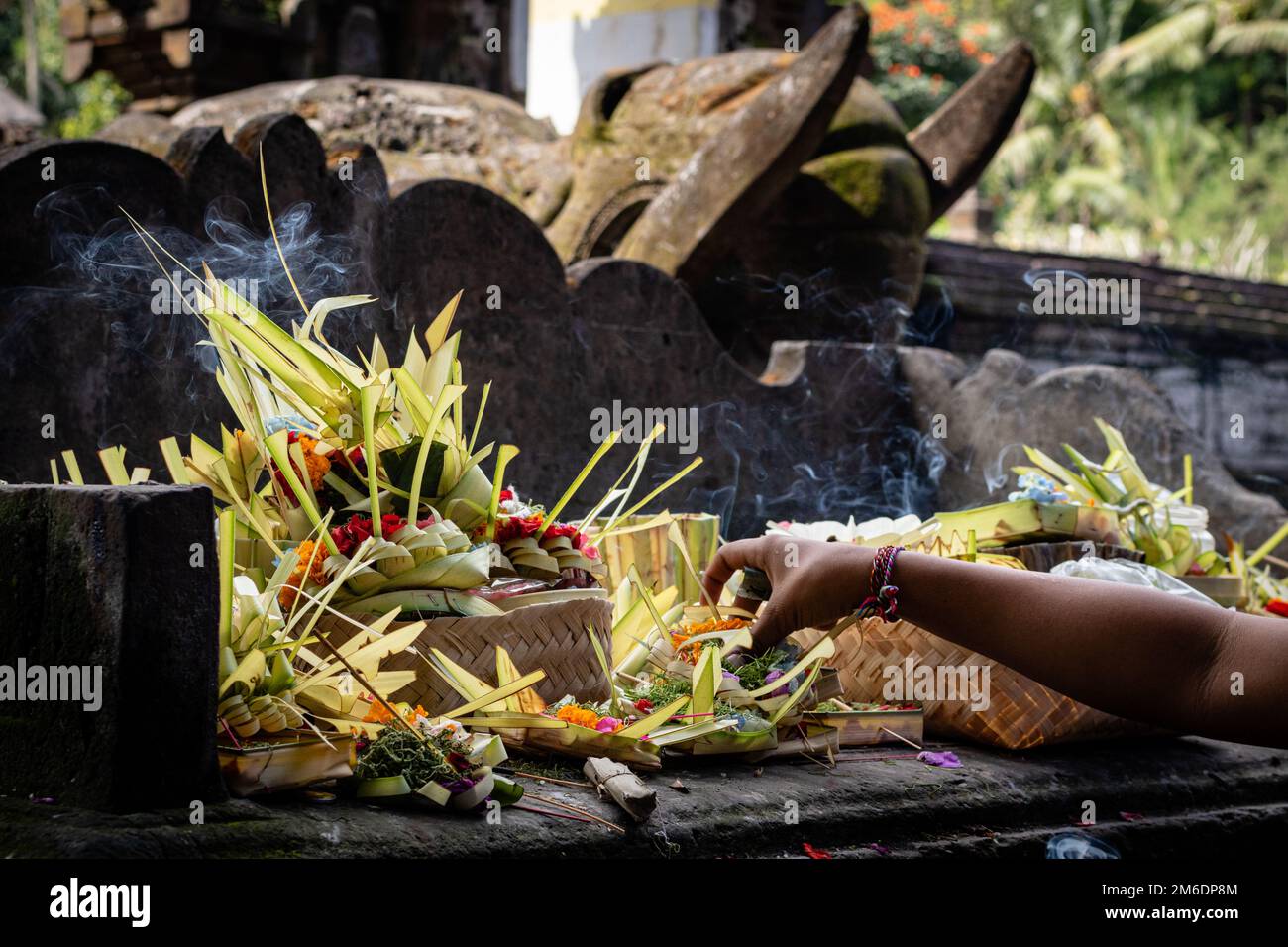 Una mano che mette incenso bruciante in un'offerta ad un tempio Balinese Foto Stock