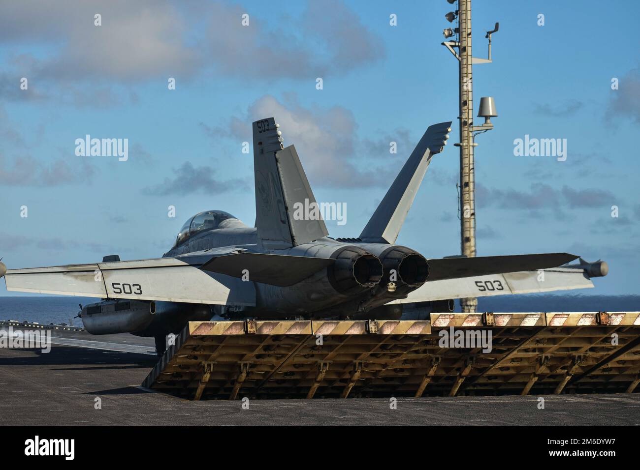 MARE DELLE FILIPPINE (25 aprile 2022) Un deflettore di jet blast viene sollevato come un EA-18G Growler, assegnato ai 'Wizards' di Electronic Attack Squadron (VAQ) 133, si prepara a lanciare dal ponte di volo della portaerei di classe Nimitz USS Abraham Lincoln (CVN 72). Abraham Lincoln Strike Group è in programma di implementazione nell'area delle operazioni della flotta 7th degli Stati Uniti per migliorare l'interoperabilità attraverso alleanze e partnership, mentre funge da forza di risposta pronta a sostegno di una regione indomoresanacea libera e aperta. Foto Stock