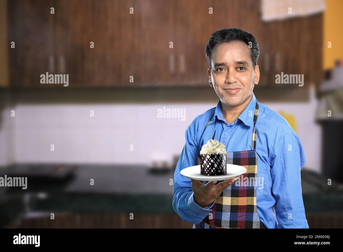 Chef indiano maschile con una torta dolce con interni cucina Foto Stock