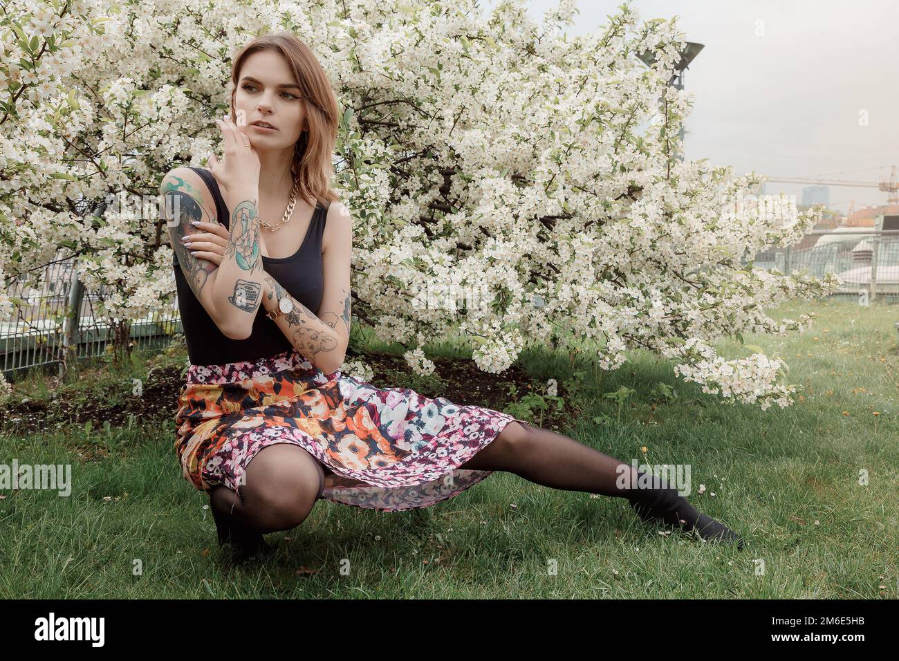 Ragazza elegante vicino ai cespugli fioriti in bianco. Posa di moda. Donna in primavera. Foto Stock