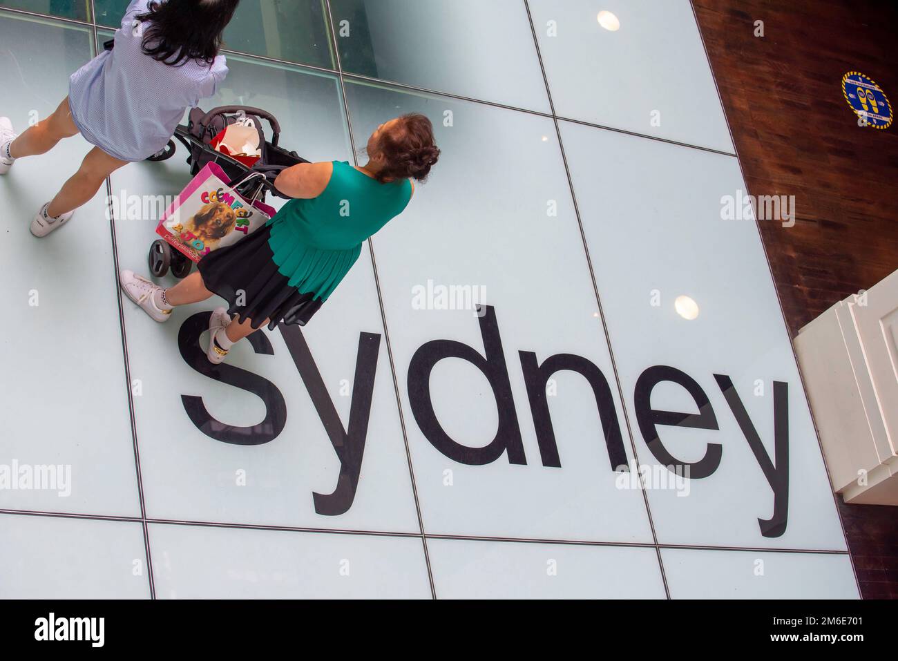 Persone che si trovano sopra la parola Sydney, impressa sul pavimento di vetro della Dogana, Sydney, Australia, che copre un grande modello del CBD della città. Foto Stock