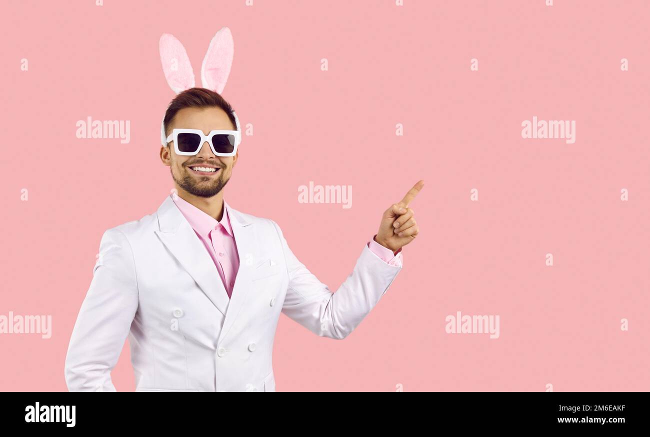 Un uomo sorridente in orecchie conigliate punta nello spazio copia Foto Stock