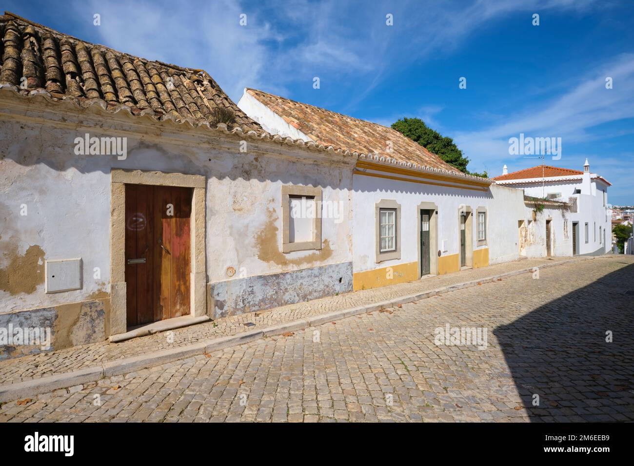 Una visione di tipico, generico, vecchio, povero, umile, Semplice casa moresca, architettura domestica con pareti in stucco peeling, tetti in tegole arancioni spagnole. A Tavira Foto Stock