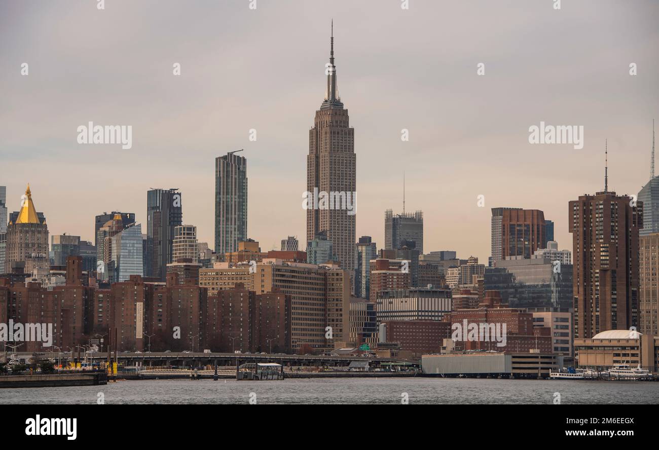 Lo skyline di Midtown Manhattan, che include l'Empire state Building e i blocchi di appartamenti accanto all'East River Park Field, New York City Foto Stock