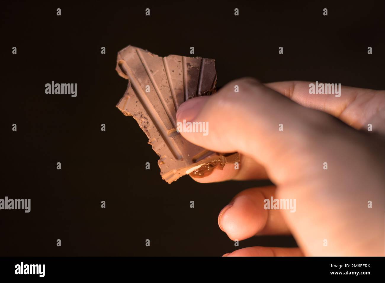 Un pezzo di cioccolato fondente in una mano femminile. Fuori fuoco  Fotografia naturale candida. Notte Foto stock - Alamy