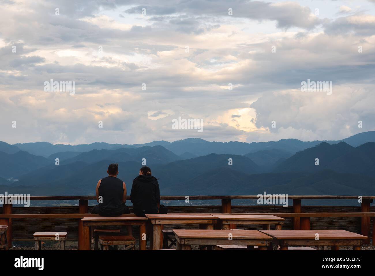 Due persone che guardano il paesaggio montano seduti con le spalle alla fotocamera Foto Stock