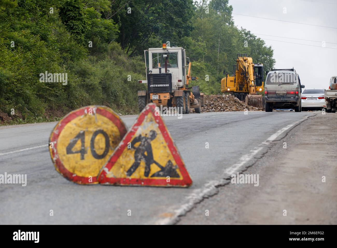 Estate, 2016 - Primorsky Krai, Russia - Riparazione di una strada malfunzionante. I lavoratori spianano una strada sbagliata in una foresta in Russia. Foto Stock