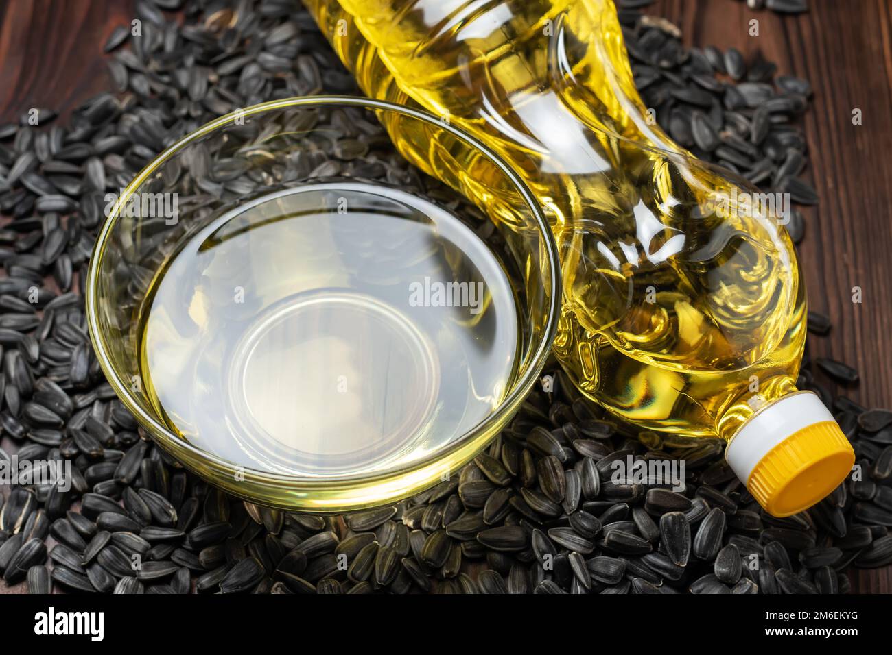 Olio di girasole biologico in una ciotola di vetro e bottiglia con semi di girasole Foto Stock