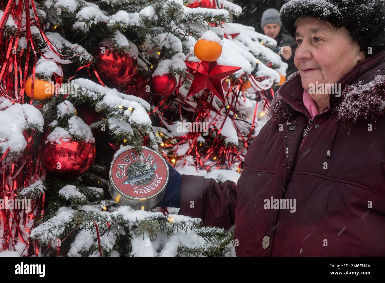 Mosca, Russia. 3rd gennaio 2023. Una donna anziana scatta una foto con un vasetto di caviale, che decora l'albero di Natale, sulla via Kuznetsky Most, nel centro di Mosca, Russia Foto Stock