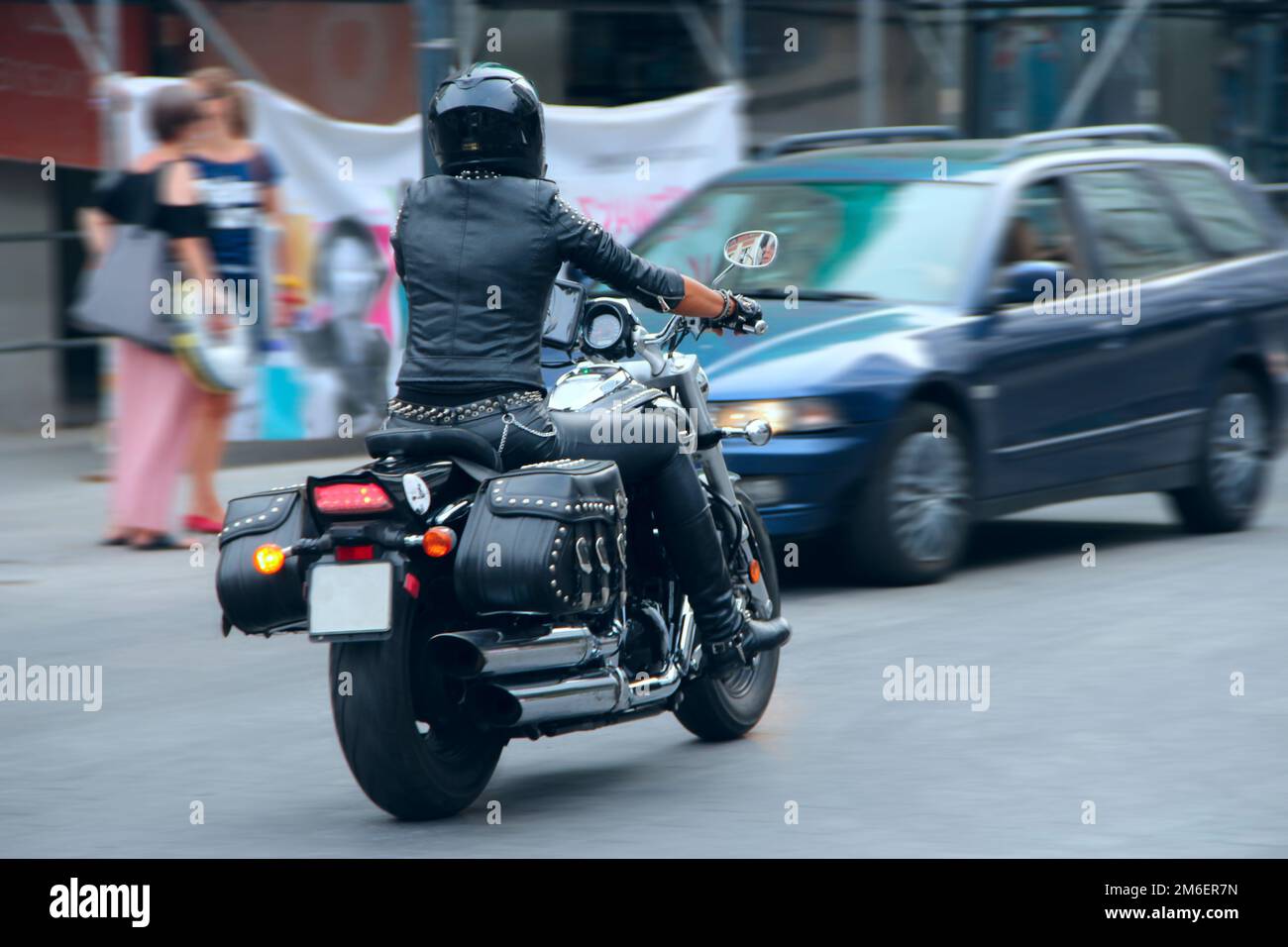 Ragazza elegante in pelle nera vestito guida su moto. Motociclista femminile che indossa la prosa Foto Stock