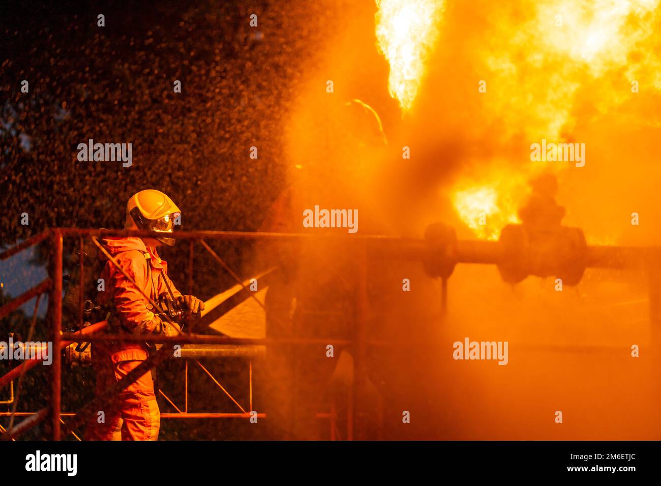 Vigili del fuoco che utilizzano la nebbia d'acqua per spruzzare il fuoco dalla piattaforma petrolifera esplosione in fabbrica Foto Stock